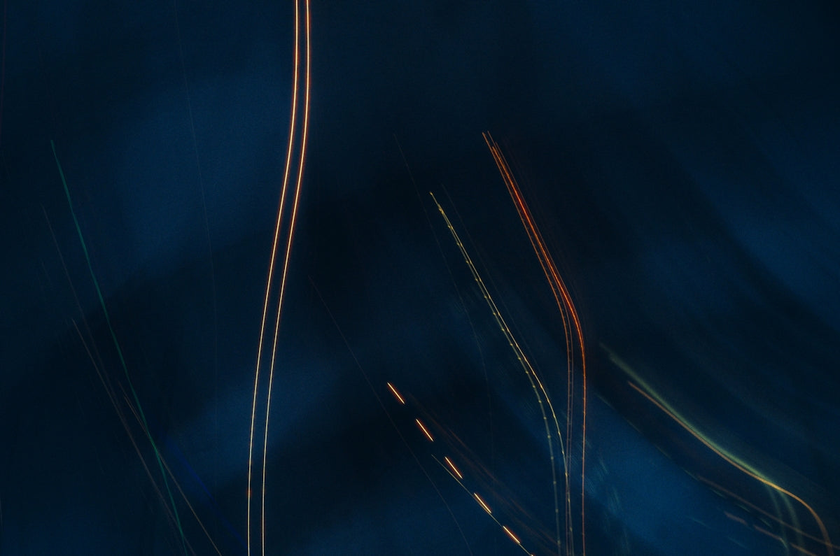 Abstract light trails against a dark blue backdrop.