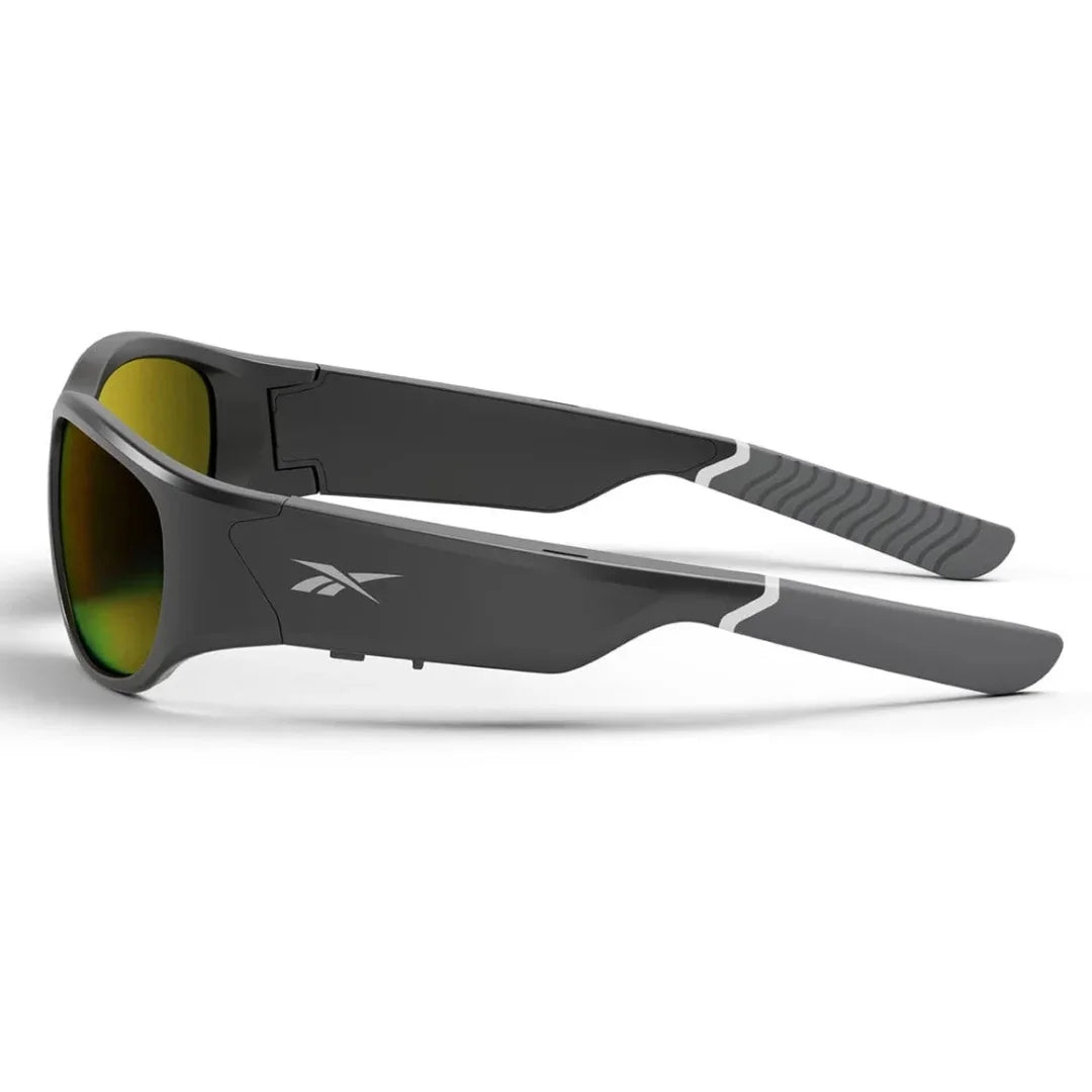 Vista cenital de gafas deportivas Reebok negras con lentes amarillas, mostrando el diseño ergonómico y el agarre de las patillas.