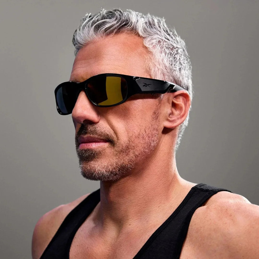 Hombre en primer plano usando gafas deportivas negras con lentes amarillas de alto contraste, para entrenamiento o conducción.