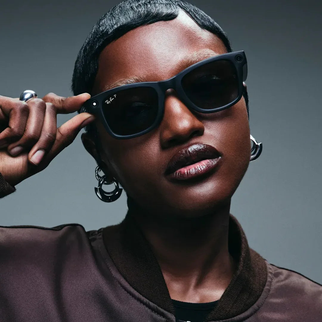 Primer plano de una modelo con cabello corto y chaqueta café, usando las gafas de sol inteligentes Ray-Ban Meta Wayfarer en negro mate.