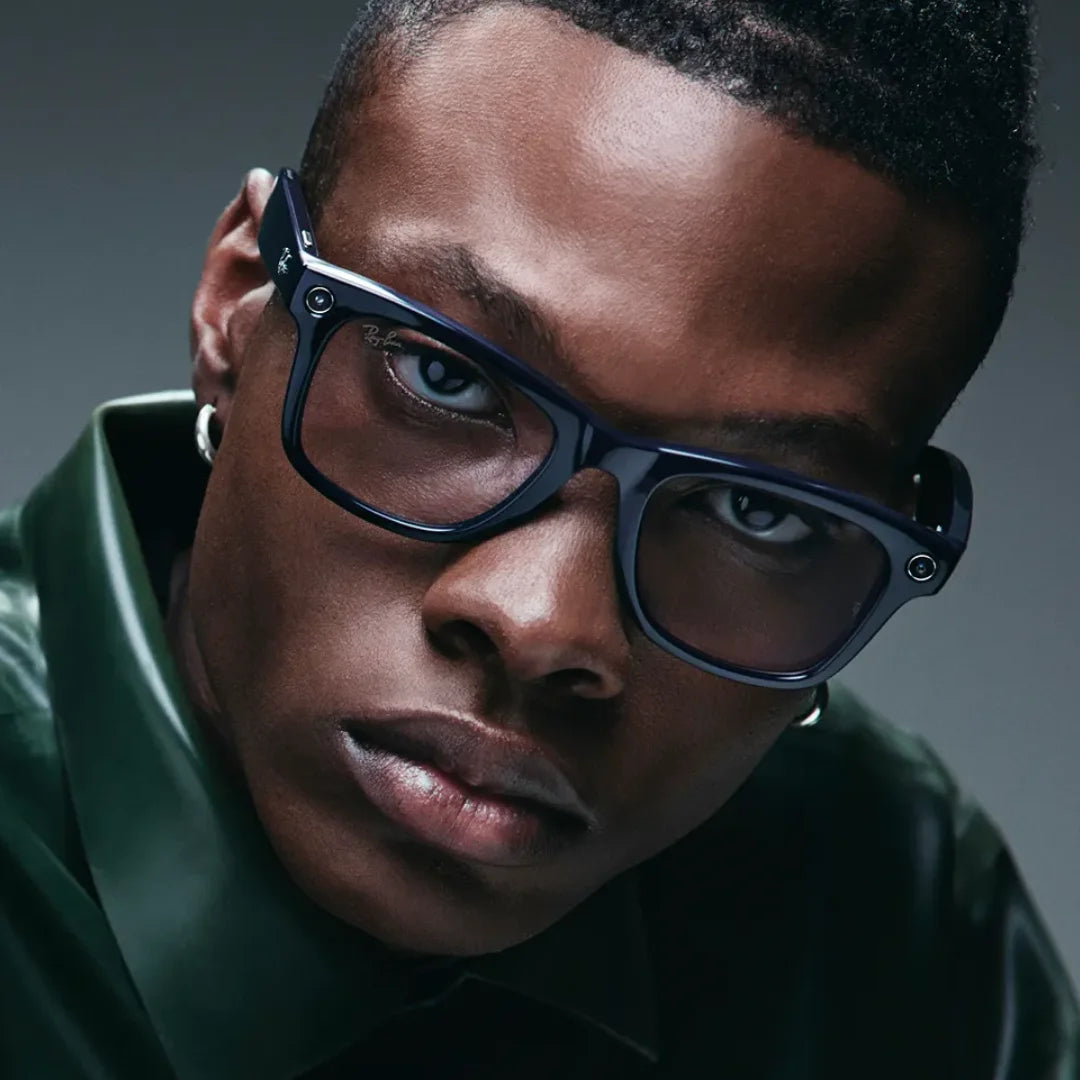 Primer plano de un modelo usando las gafas inteligentes Ray-Ban Meta Wayfarer con montura azul cósmico y lentes transparentes/ligeramente tintadas.